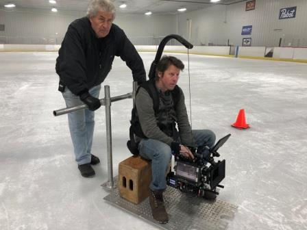 Tommy Cheatham operating a custom ice dolly camera setup during a professional production on an ice rink